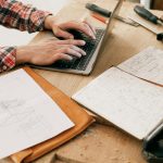A woodworker uses a laptop to design furniture in a workshop setting, highlighting the blend of technology and craftsmanship.